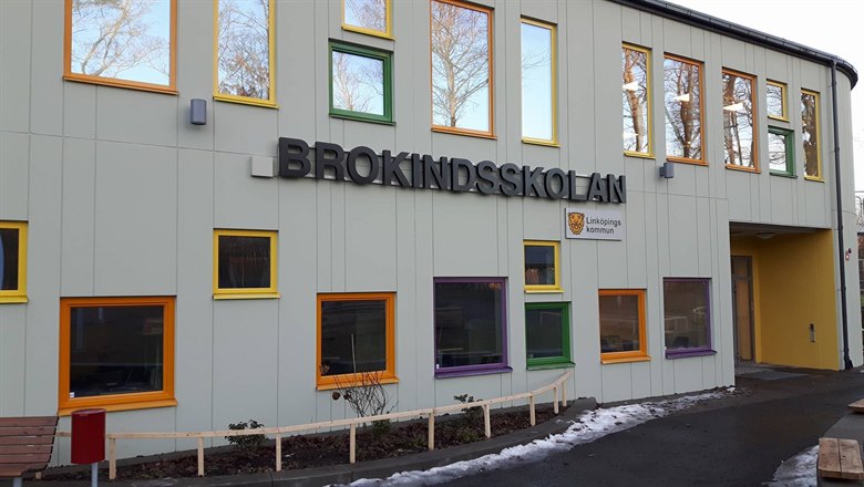 Framsidan på Brokinds skola med en massa fönster med olika fäger på ramarna. Lite snö vid kanten på rabatten framför.