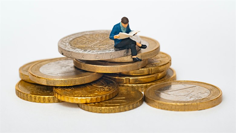 En figur som sitter på en hög med mynt.