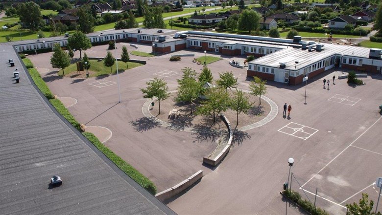 Vy över Linghemsskolans hästskoformade byggnad och skolgård i mitten