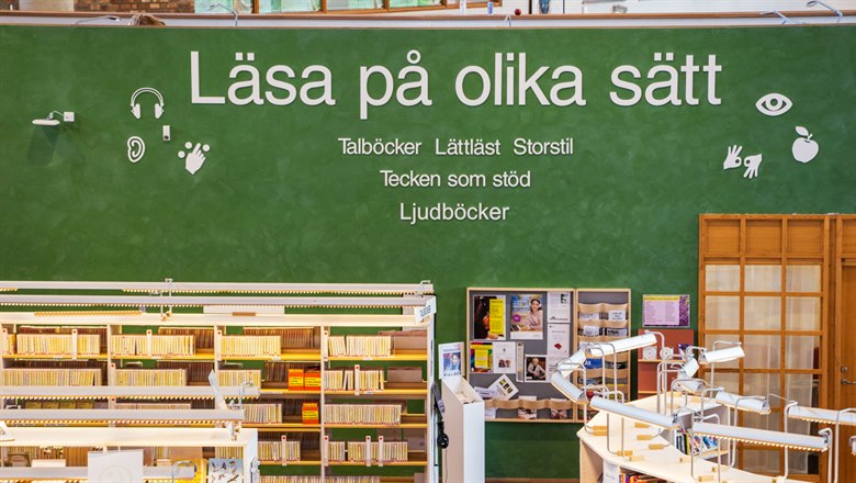 En grön tavla med texten "Läsa på olika sätt". Nedanför den står bokhyllor.