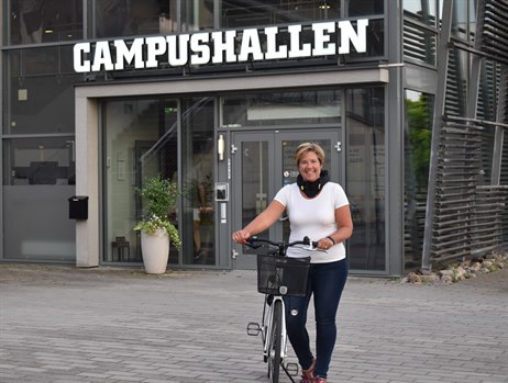 Kvinna med cykel utanför Campushallen