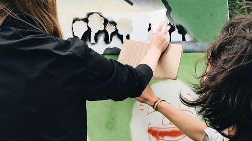 Barn målar regnbågar på en vägg