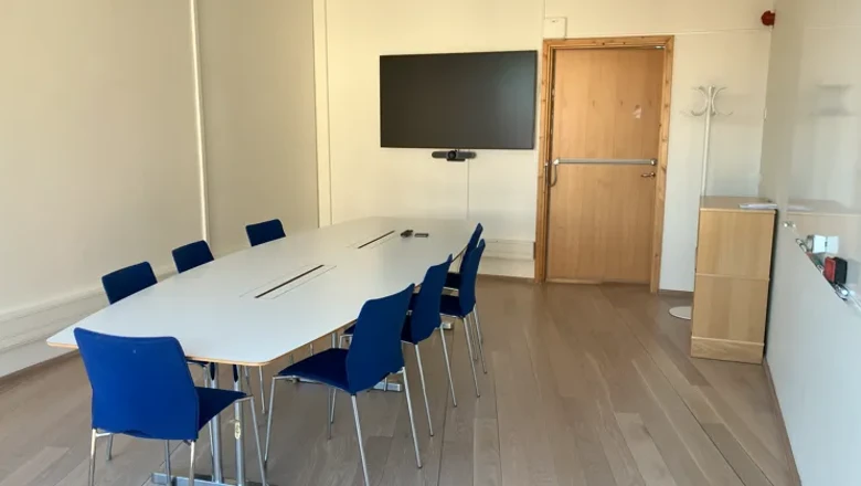 Ett konferensrum med ett stort vitt bord och blå stolar.