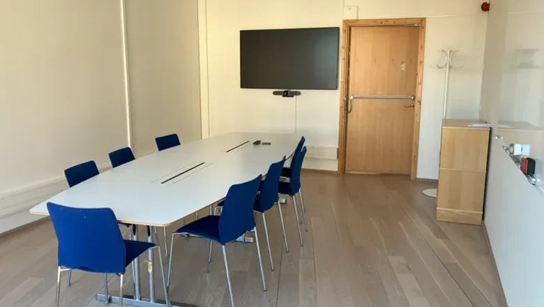 Ett konferensrum med ett stort vitt bord och blå stolar.