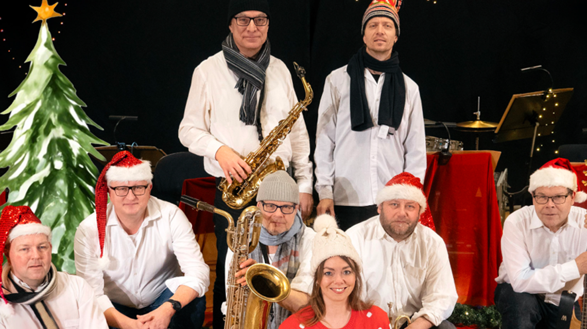 En grupp människor i julkläder som poserar med olika instrument.