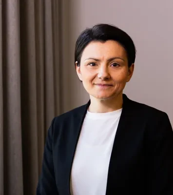 En kvinna som står bredvid ett fönster i ett rum.