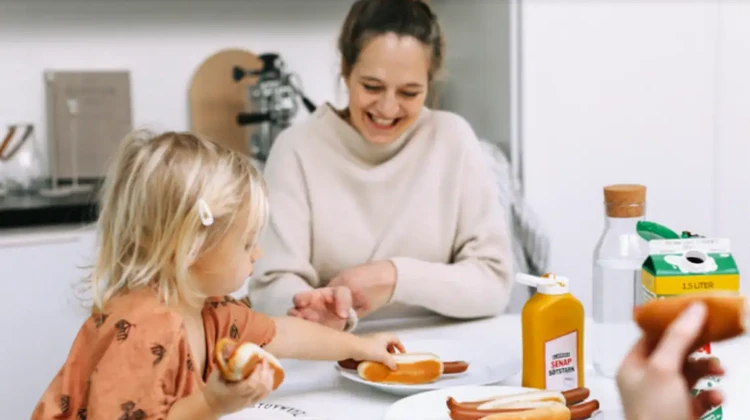 vuxen kvinna och ett barn sitter vid ett matbord.