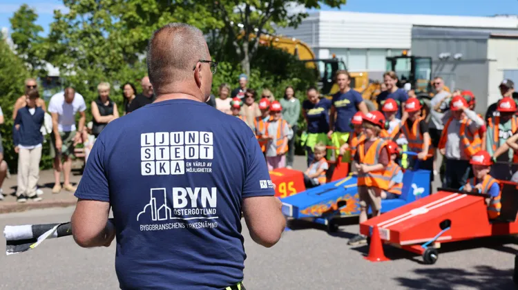 Man i förgrunden, barn och lådbilar i bakgrunden