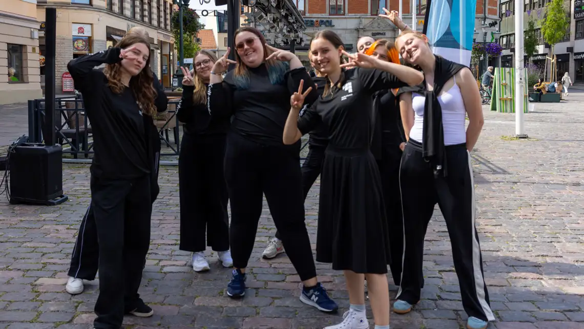 8 dansare tittar och ler mot kameran.