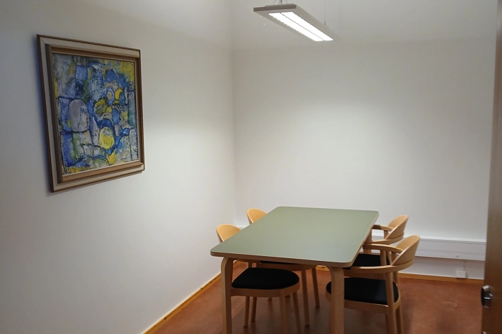 Ett bord och stolar i ett rum med en målning på väggen.