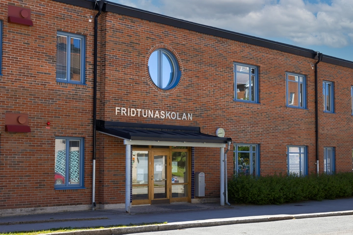 En byggnad i rött tegel med blå fönster.
