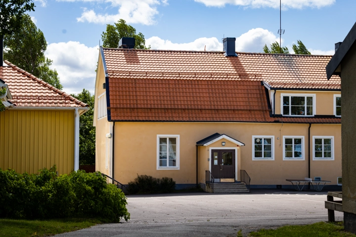 Ett gult hus med rött tak och vita fönster.