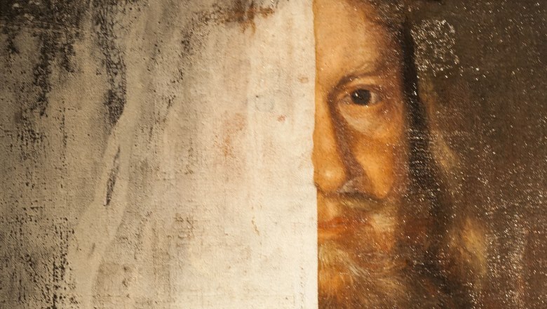 Oljemålat ansikte av en skäggig man från renässansen. Täckt till hälften av svart och vit färg. 