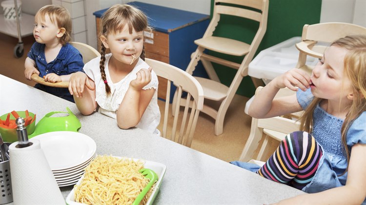 Flera barn sitter vid ett bord och äter mat