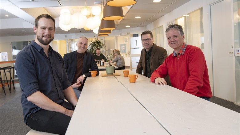 Fyra män runt ett bord i en kontorsmiljö.