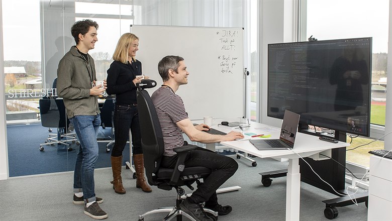 Tre medarbetare på Axis arbetar tillsammans vid en stor datorskärm.