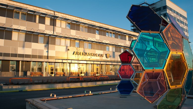 Arenaskolans byggnad med konstverk i förgrunden i form av en fotboll i färgat glas