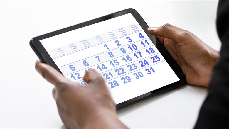 Ett par händer håller en iPad med en kalender synlig