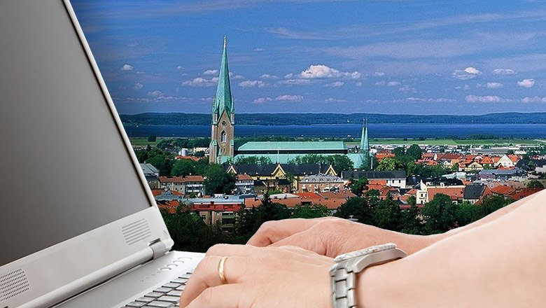 Två händer som skriver på en dator. Bakgrunden är vyn över Linköpings domkyrka