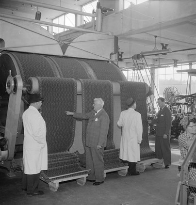 Ebbe och flera andra personer framför företagets mattillverkning 1950