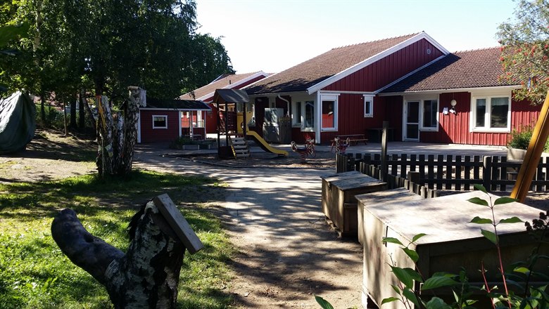 Lingonvägens förskola och gård, med det röda huset, klätterställning och en koja