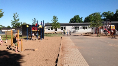 Skolgård med lekplats och klätterredskap i förgrunden