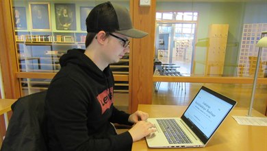 Student vid skrivbord söker via laptop i stadsfullmäktigeprotokoll