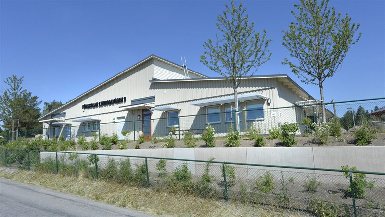 Förskolan Lerbogavägen 9 med sin vita träbyggnad och planteringar av buskar och träd i förgrunden