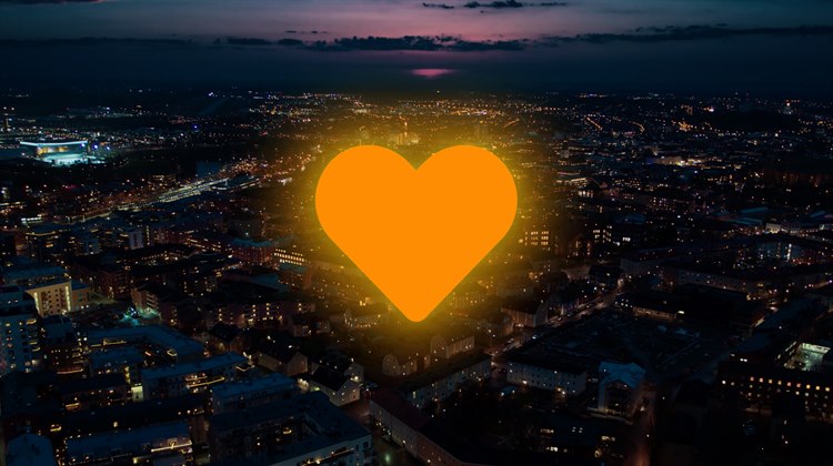 Ett lysande gult hjärta över ett mörklagt Linköping.