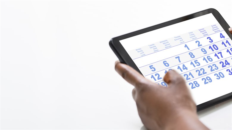 Ett par händer håller en iPad med en kalender synlig