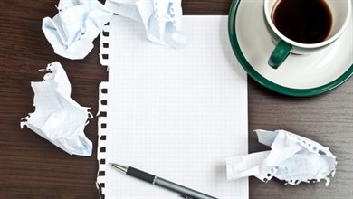 Kaffekopp, papper och penna på ett bord