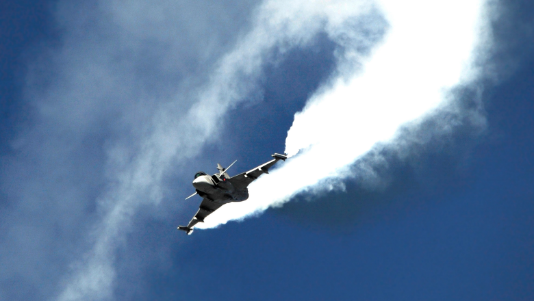 Ett Gripen-flygplan på en blå himmel med en vit luftström efter sig