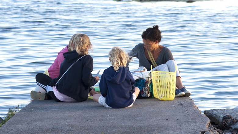 Bild på en mamma med barn på en brygga vid vattnet