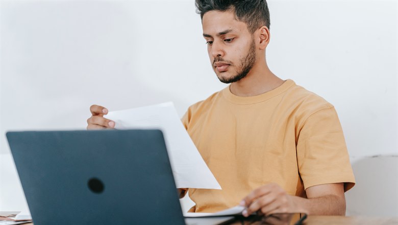 En man sitter framför en dator och läser ett dokument.